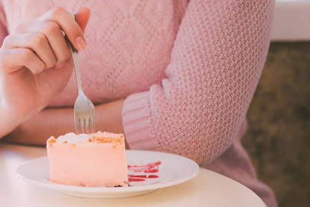 女人在桌子前吃叉蛋糕