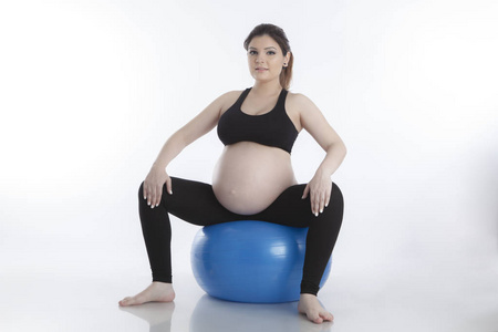 孕妇在白色背景下练习体操球