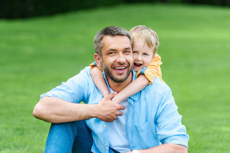 快乐的父亲和儿子拥抱和微笑在照相机在公园