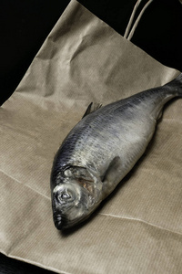 盐水鲱鱼鱼在纸袋子背景。乡村风格