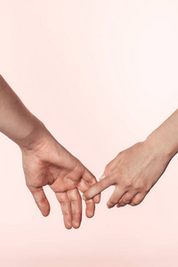 在粉红色背景下被手指隔离的妇女手持男子手的裁剪照片