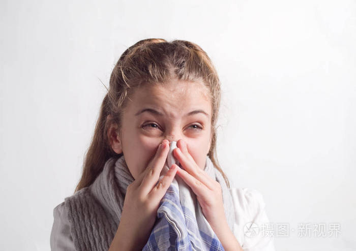 女孩在灰色背景下擤鼻涕
