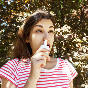 一个女人在鼻子里滴鼻涕。疾病和疾病。治疗鼻窦炎和过敏。医疗理念