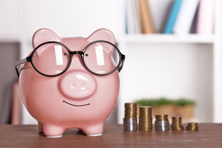 储钱罐在家里或办公室的背景上的硬币眼镜照片