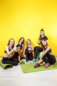 青年体育妇女的小组在黄色背景上显示拇指