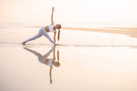 练瑜伽在海滨的热带海洋的白种女人