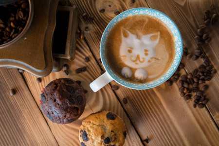 猫泡沫的面孔拿铁艺术咖啡在杯子与散落的咖啡豆和饼干在老木桌