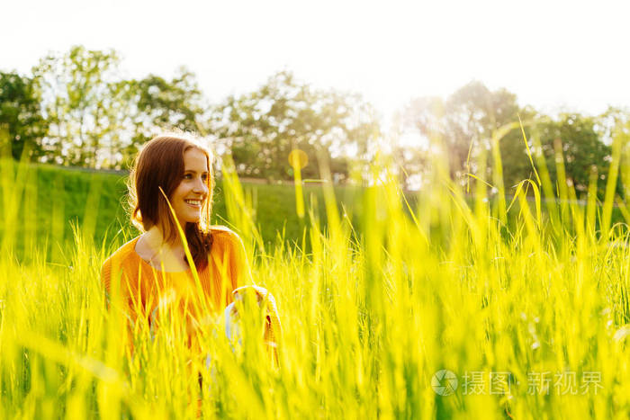 阳光下坐在草地上笑的年轻女子