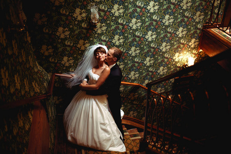 漂亮的婚礼情侣拥抱在老在一个木制的大厅楼梯上