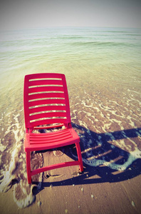 红色塑料躺椅一样无济于事在海岸边以复古作用