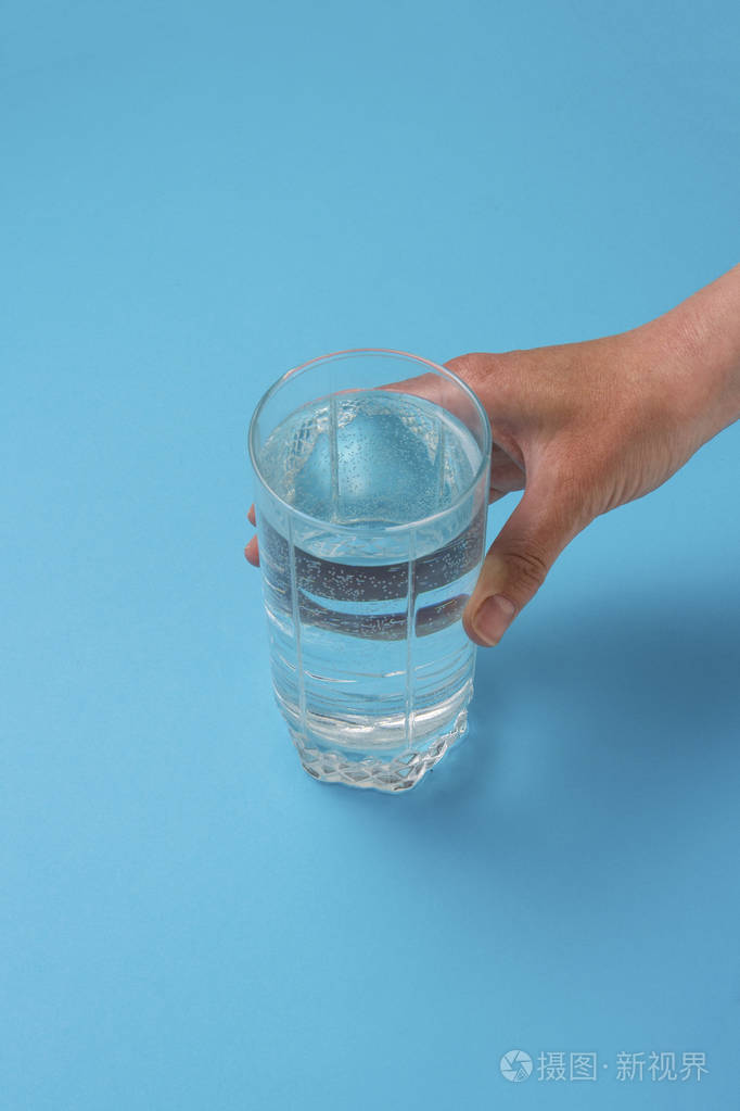 女性手拿一杯水在蓝色背景上