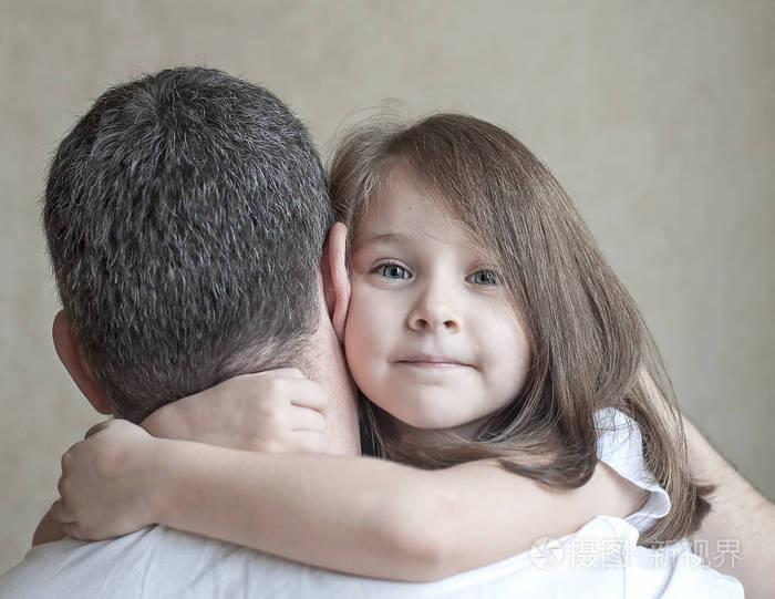 可爱的小女孩的肖像举行在父亲的怀抱.幸福美满的家庭.父亲和他的女儿