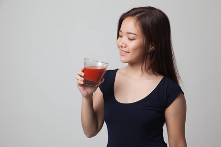 年轻的亚洲女人喝番茄汁