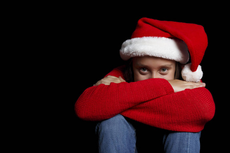 圣诞快乐。穿着红色毛衣和圣诞老人帽子的那个年轻女孩正躺在她的手上, 微笑着。黑隔离。复制空间