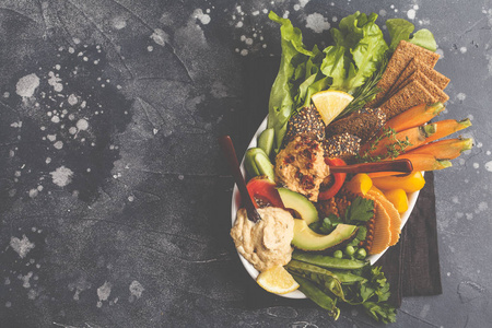 素食阿拉伯语蘸鹰嘴豆泥与蔬菜和不同的零食在白色板上的黑暗背景。健康素食概念