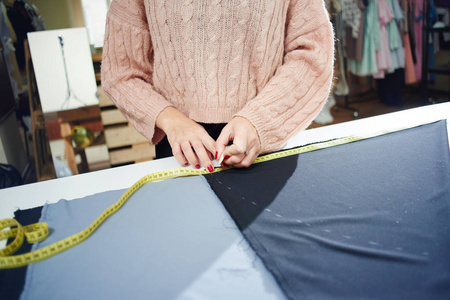 裁缝与测量磁带测量纺织品在工作台, 特写