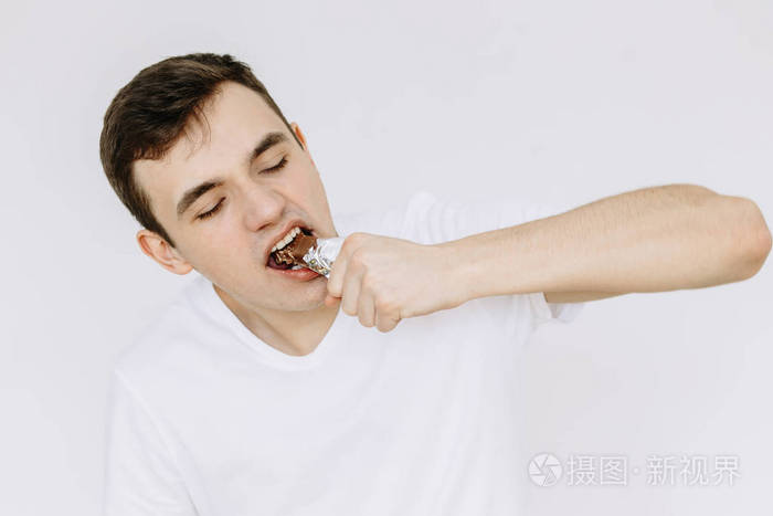 一个小男孩正在吃巧克力糖分离的白色bac