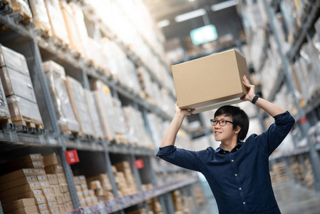 在仓库, 购物仓储或工作挑选和包装概念的货架上, 年轻的亚洲男子背着纸板箱头