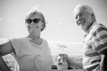 两个老年人喝果汁的屋顶露台与美丽的海景。休假和退休概念