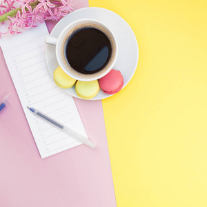 创意广场平躺照片的咖啡杯与杏仁和一个记事本与复制空间的粉红色和黄色背景最小的风格