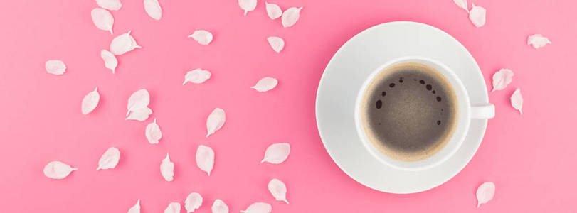 创意平躺概念咖啡杯和白色苹果树花花瓣在柔和的粉红色背景与拷贝空间在极小的样式, 长宽横幅
