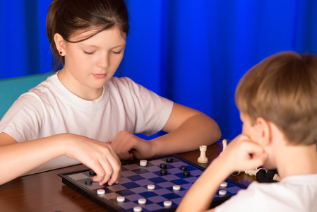 儿童男孩和女孩玩棋盘游戏叫跳棋