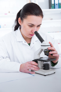 女人用显微镜在实验室里工作。色调图像