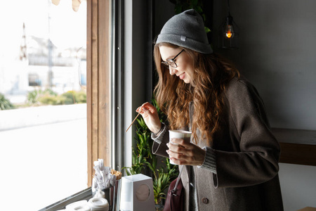 年轻漂亮的女人快乐在咖啡馆里喝咖啡