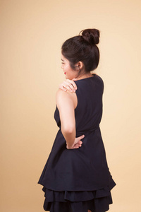 年轻的亚裔妇女背部疼痛的米色背景