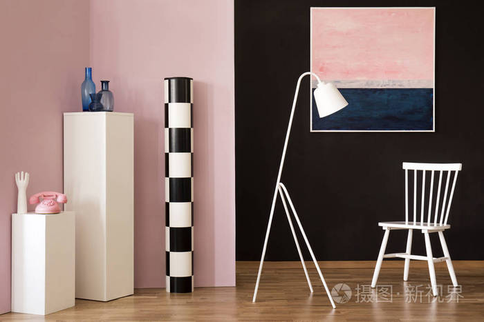 白色灯在客厅的椅子旁边与粉彩绘画和粉红色电话在基座上