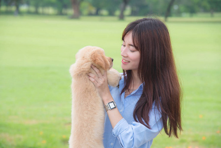 美丽的亚洲女孩微笑与她的小狗在公园里