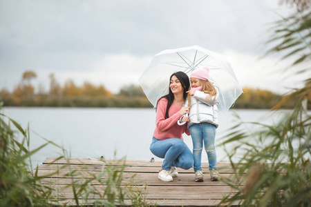 年轻的母亲与她的小女儿在秋天时间在湖附近