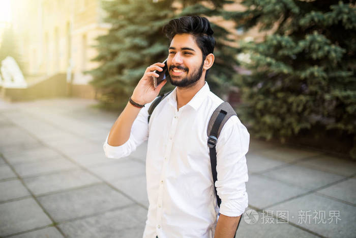 年轻英俊的印度男人谈电话市区内的肖像