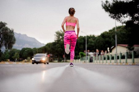 在阴天的高速公路上穿着粉红色运动服的年轻女子的背景色