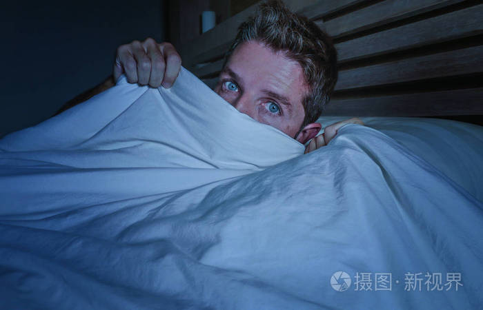 惊恐的恐怖噩梦覆盖脸上的毯子睡不着床躺在黑暗的卧室睡觉混乱的概念