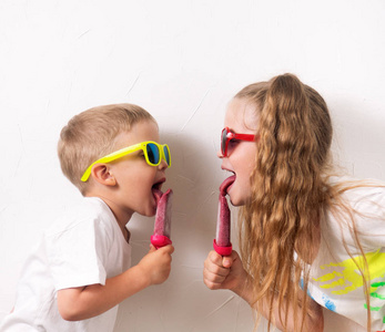 儿童夏日甜点 儿童男孩和女孩在太阳镜和有色 t恤衫, 在白色背景下吃粉红色的家庭冰淇淋。肖像。方形框架