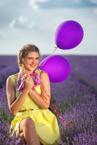 一个快乐和快乐的女孩的肖像在黄色的礼服与气球在她的手中。在背景中, 薰衣草田野和蓝天。垂直框式射击