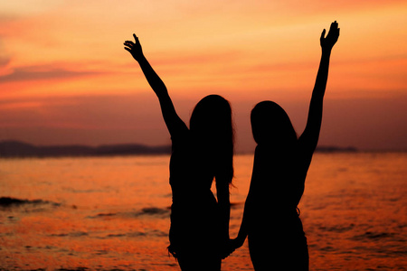 两位年轻女子在海边玩的剪影