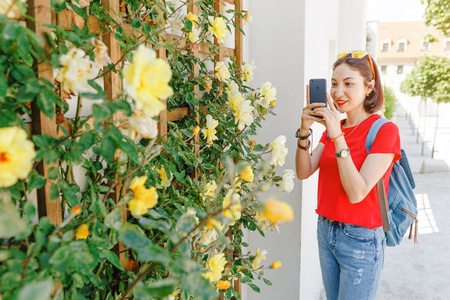 女孩 instagram 博客使用她的智能手机在花园里花的照片