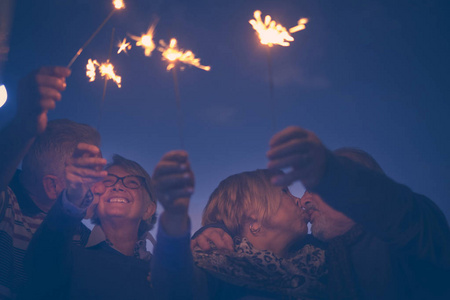 庆祝晚会为假日夜或新年前夕2019。一群有火火花的老年男女。每个人晚上接吻和有很多乐趣