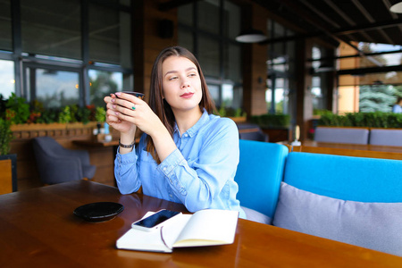 女商人在咖啡馆里与智能手机笔记本和咖啡杯一起休息