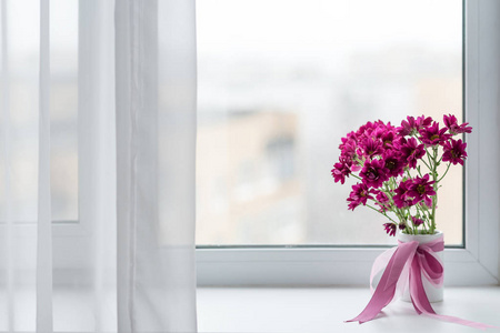 粉红色的菊花束插在花瓶里在窗口背景