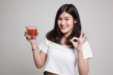 年轻的亚洲女人表演 Ok 用西红柿汁