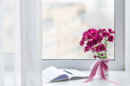 粉红色的菊花束插在花瓶里在窗口背景