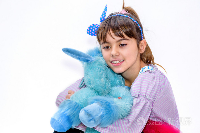 快乐的小女孩抱着蓝色独角兽玩具上白色孤立
