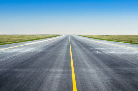 沥青路面,通过绿色的田野和蓝天在夏季的一天照片