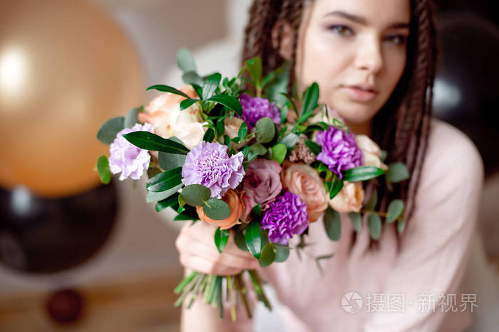 特写美丽的少女与辫子的发型捧着一束鲜花在室内
