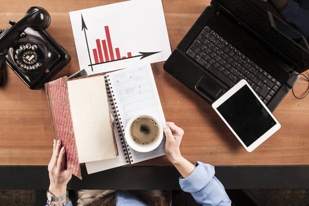 忙着雇主秘书处理办公室的文书工作, 手里拿着咖啡, 从上面查看照片