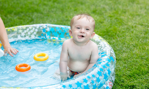 滑稽的肖像微笑的男孩游泳在充气游泳池在后院