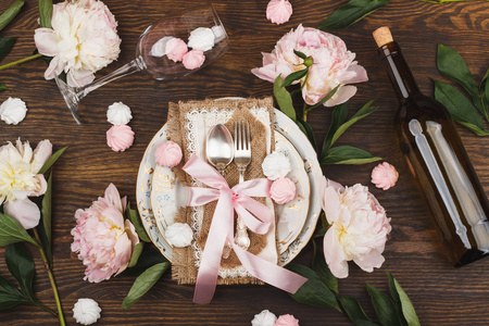 餐具和银器与浮肿光粉红色牡丹的木制的背景